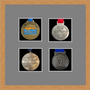 Light woodgrain picture frame for four marathon medals with grey mount